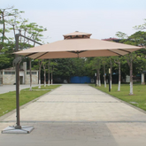 Large beige patio umbrella on a wooden deck with trees and buildings in the background